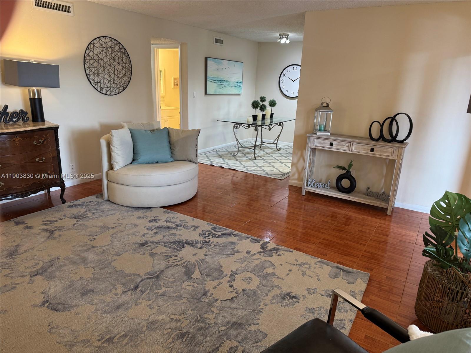 6900 Southwest 39th Street, Unit 206J Davie, FL 33314 - Photo 6 of 34 a living room with furniture a clock and wooden floor