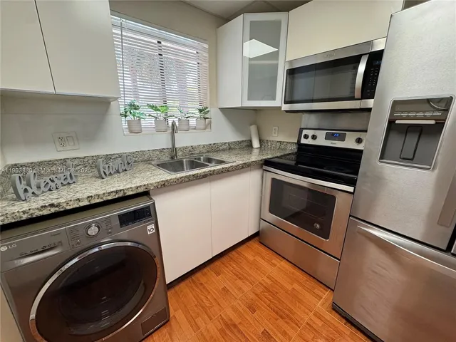 a kitchen with granite countertop a sink a stove and cabinets