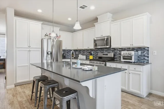 a kitchen with stainless steel appliances granite countertop a stove a refrigerator a sink a dining table and chairs with wooden floor