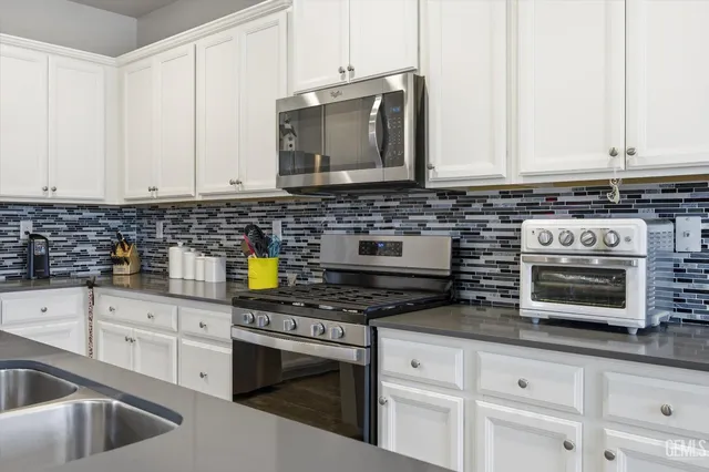 a kitchen with stainless steel appliances granite countertop a sink stove and cabinets