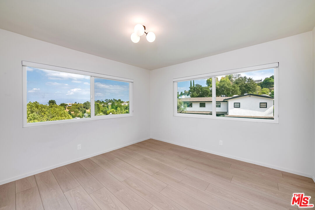 3643 Ballina Canyon Road Encino, CA 91436 - Photo 22 of 47 a view of an empty room with wooden floor and a window
