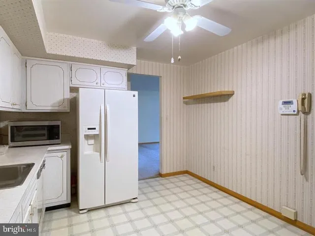 a view of a kitchen with a sink a refrigerator and cabinets