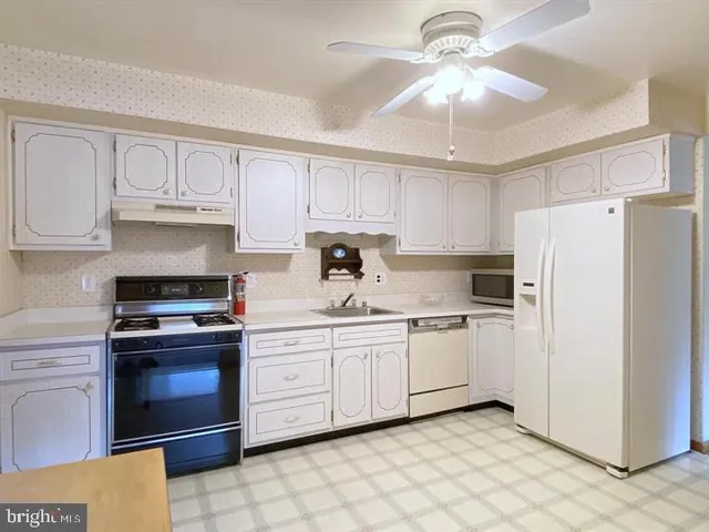 a kitchen with stainless steel appliances granite countertop a refrigerator sink and white cabinets