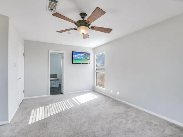 an empty room with windows and fan