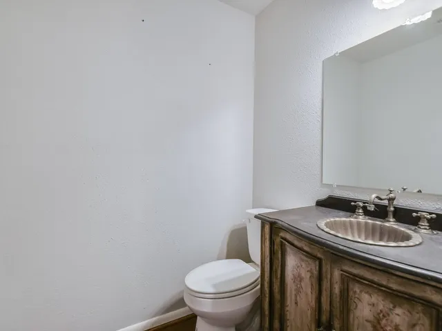 a bathroom with a granite countertop sink and a toilet