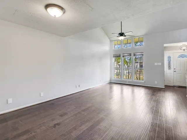 an empty room with wooden floor and chandelier