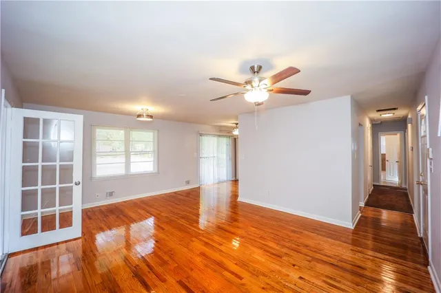 a view of an empty room with wooden floor and a window