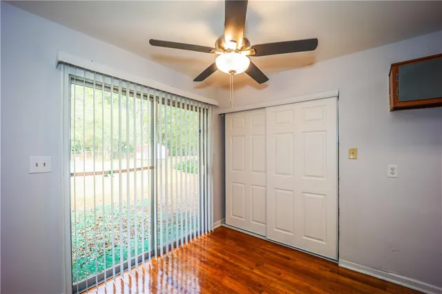 a view of empty room with wooden floor and fan