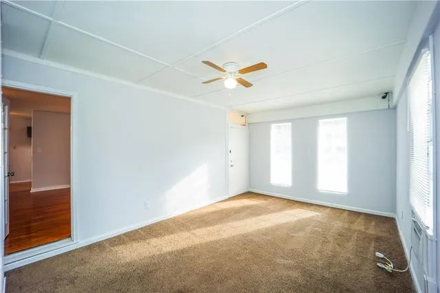 an empty room with windows and fan