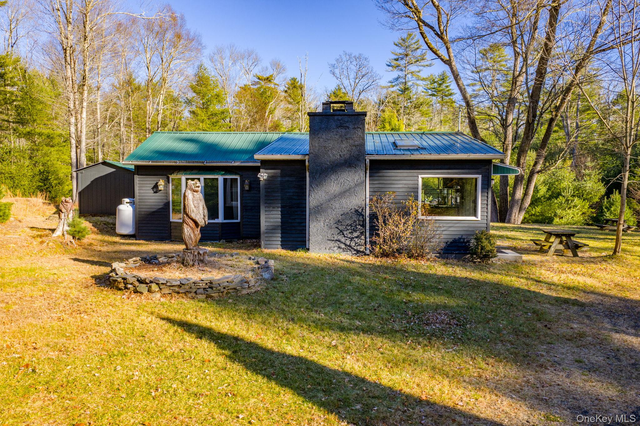 Back of property with a metal roof, a lawn, and a chimney