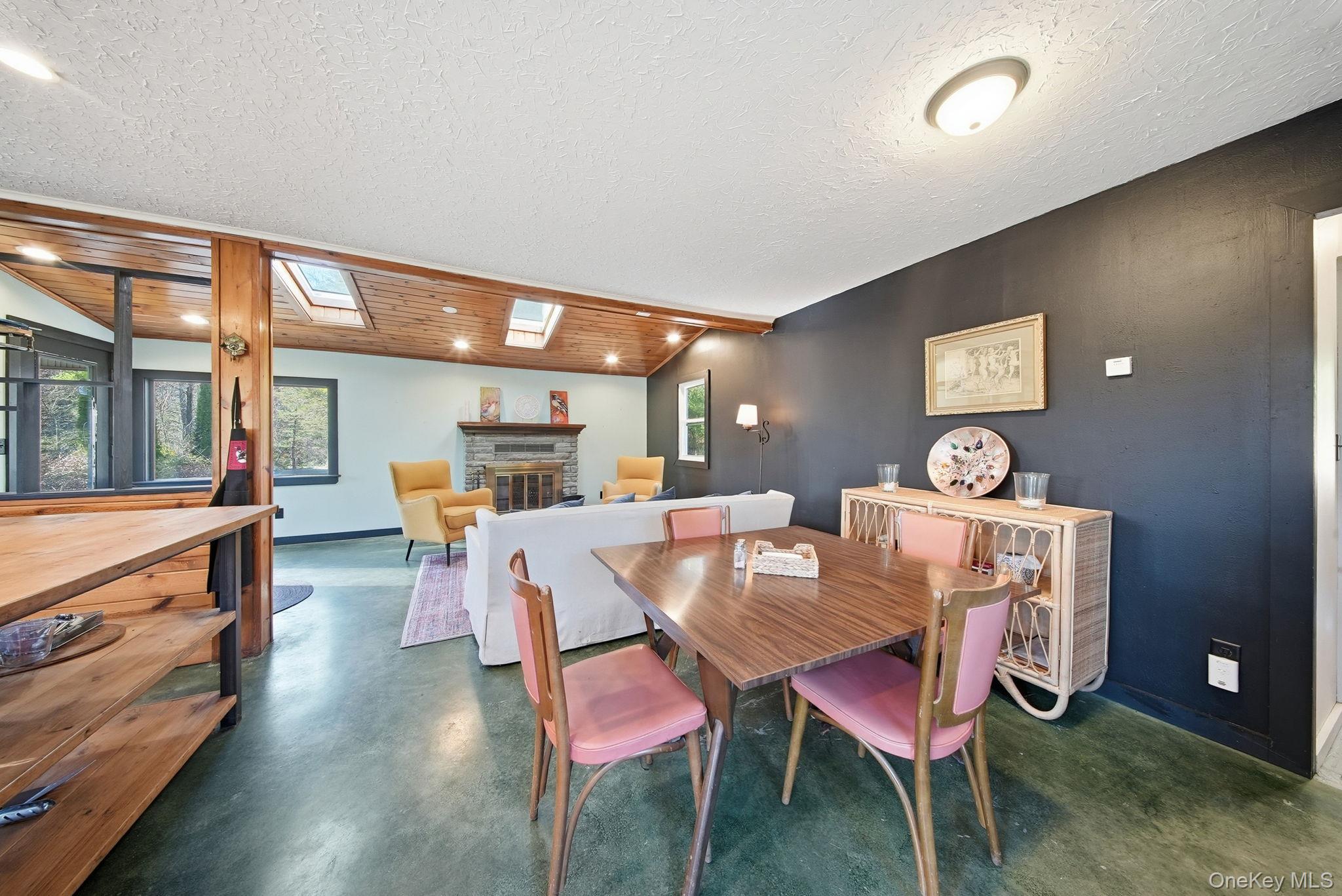 136 Barryville - Yulan Road Barryville, NY 12719 - Photo 16 of 37 Dining room with a skylight, a glass covered fireplace, concrete floors, wood ceiling, and healthy amount of natural light
