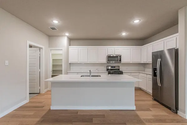 a kitchen with kitchen island stainless steel appliances a sink and a refrigerator