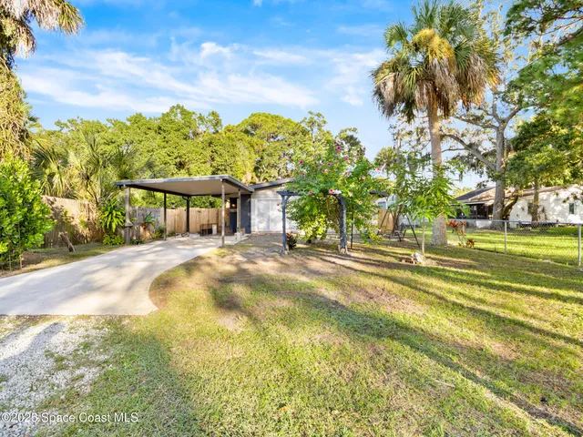 a front view of a house with a big yard and large trees