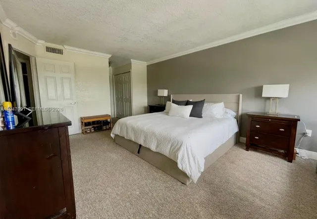 a bedroom with a bed and a flat tv screen on dresser