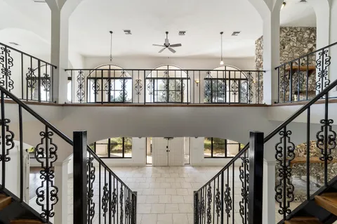 an empty room with chandelier fan and windows