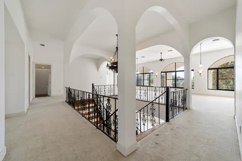 an empty room with chandelier fan and windows