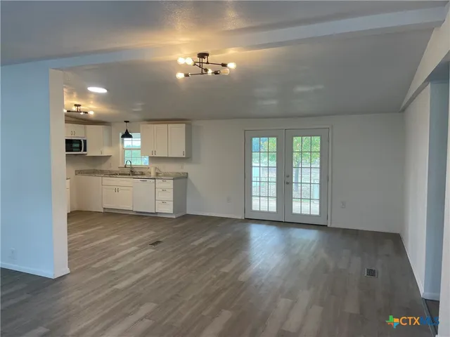 a view of a kitchen with a sink wooden cabinets and a window