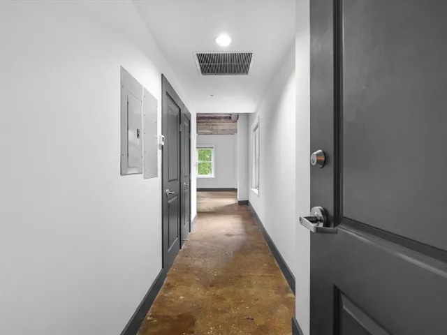 a view of a hallway with wooden floor and a bathroom