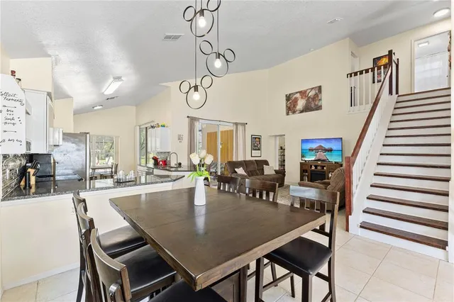 a view of a dining room and livingroom with furniture wooden floor a rug a fireplace and a chandelier