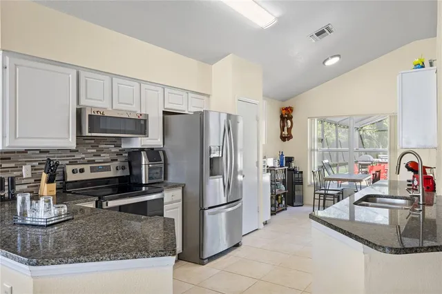 a kitchen with stainless steel appliances granite countertop a sink refrigerator and cabinets