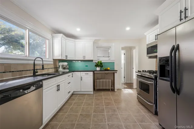 a kitchen with stainless steel appliances granite countertop a sink a stove a refrigerator and island with wooden floor