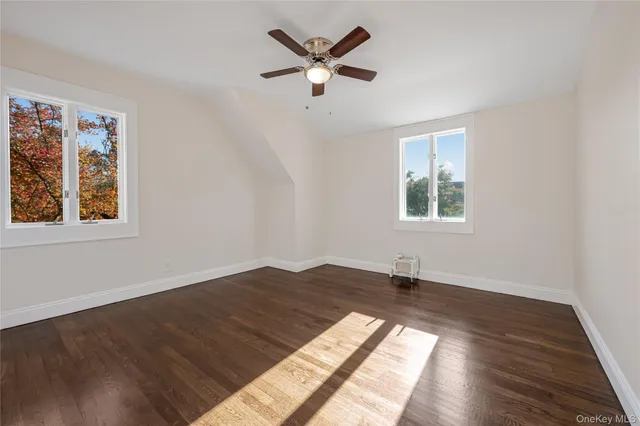 a view of an empty room with window and wooden floor