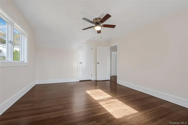 a view of empty room with wooden floor and ceiling fan