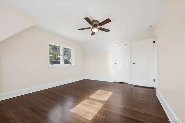 an empty room with wooden floor ceiling fan and windows