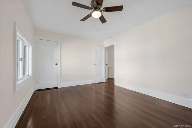 an empty room with wooden floor ceiling fan and window