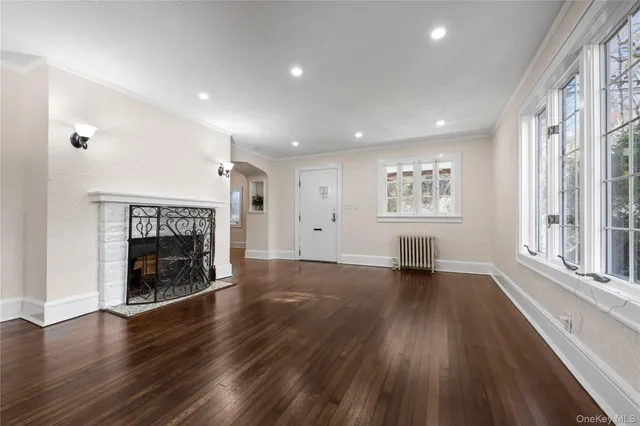 an empty room with wooden floor a fireplace and windows
