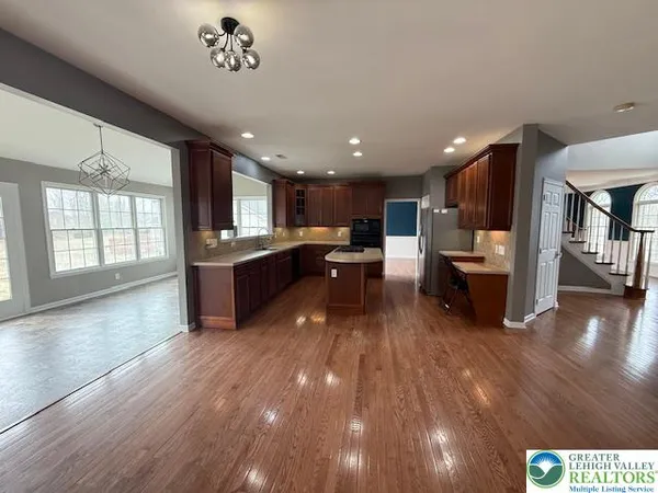 a large white kitchen with kitchen island a stove a sink a refrigerator and a dining table with wooden floor