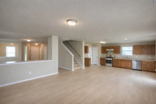 an empty room with kitchen view and window