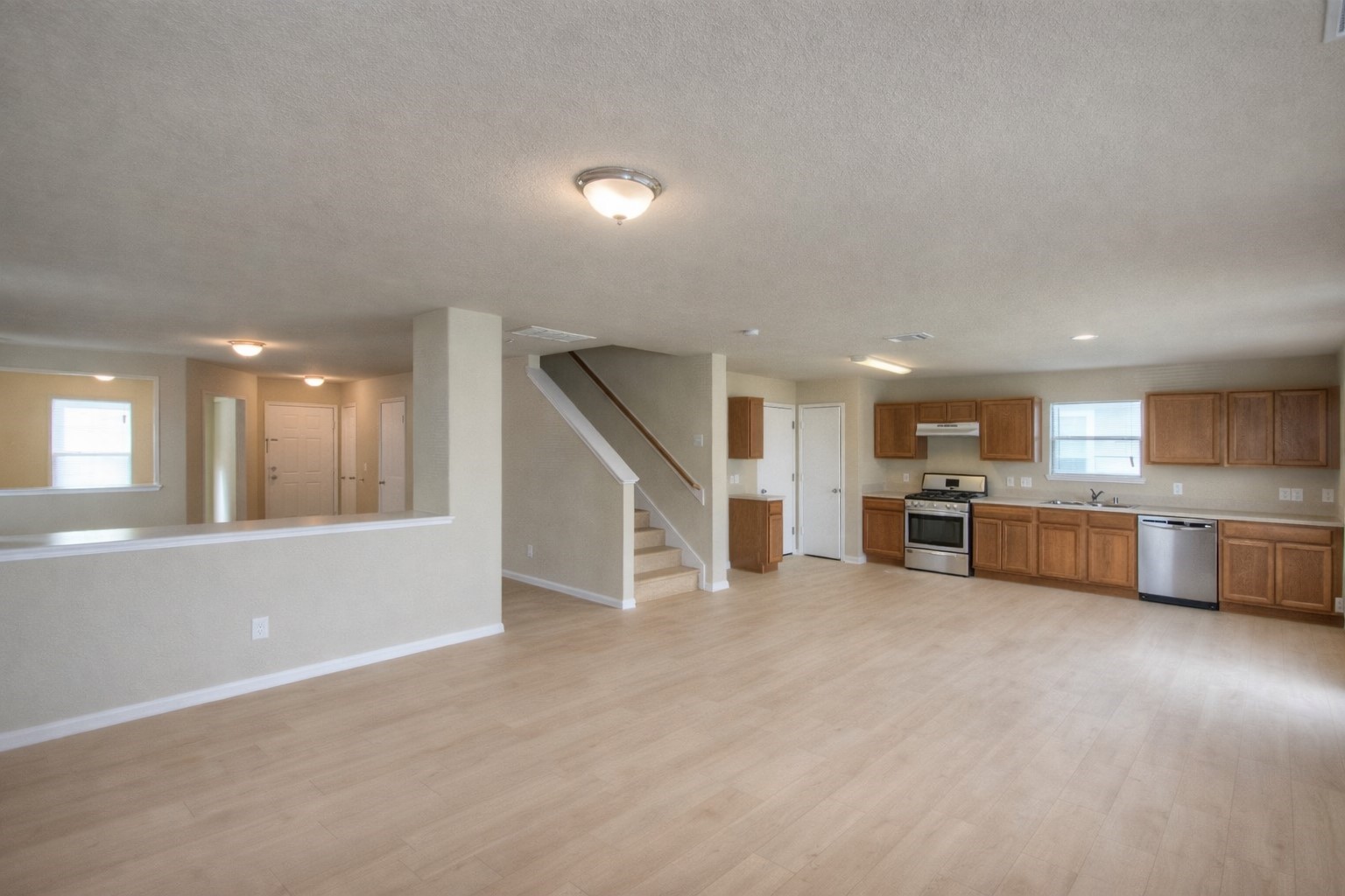 an empty room with kitchen view and window