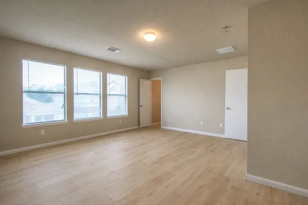 an empty room with wooden floor and windows