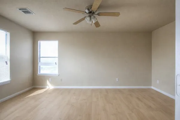 an empty room with fan and windows