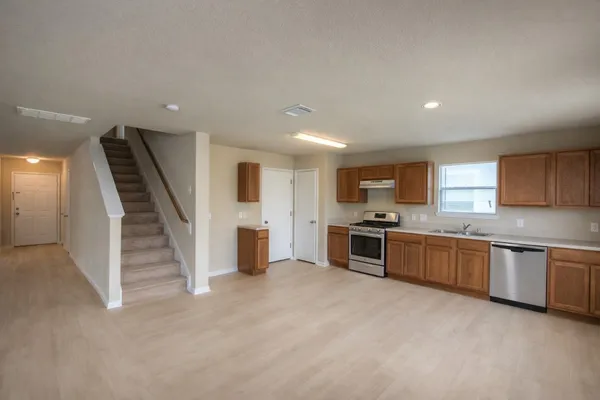 a large kitchen with a stove top oven a sink a counter space and cabinets