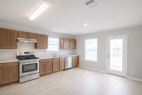 an empty room with kitchen view and a window