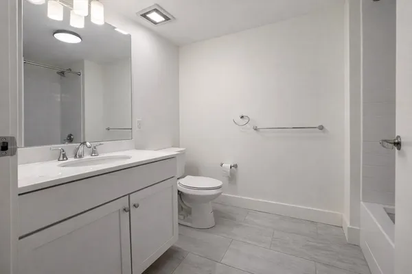 a bathroom with a toilet a sink a mirror and vanity