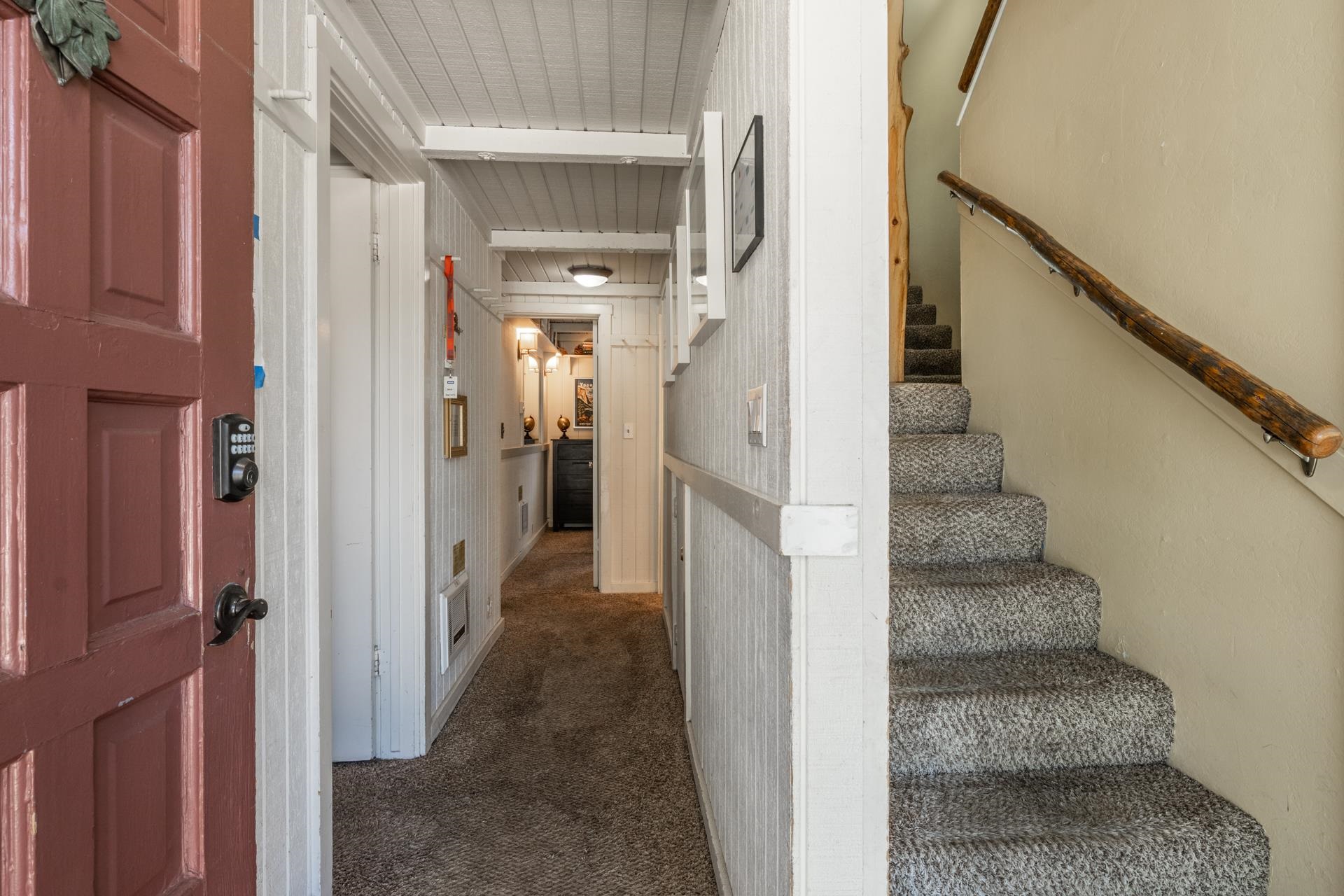 165 Old Mammoth Road, Unit 3 Mammoth Lakes, CA 93546 - Photo 31 of 48 Inviting entryway featuring a paneled front door with a digital keypad, white beadboard walls, wood-finish ceiling, and textured carpet flooring extending into the hallway and up the staircase