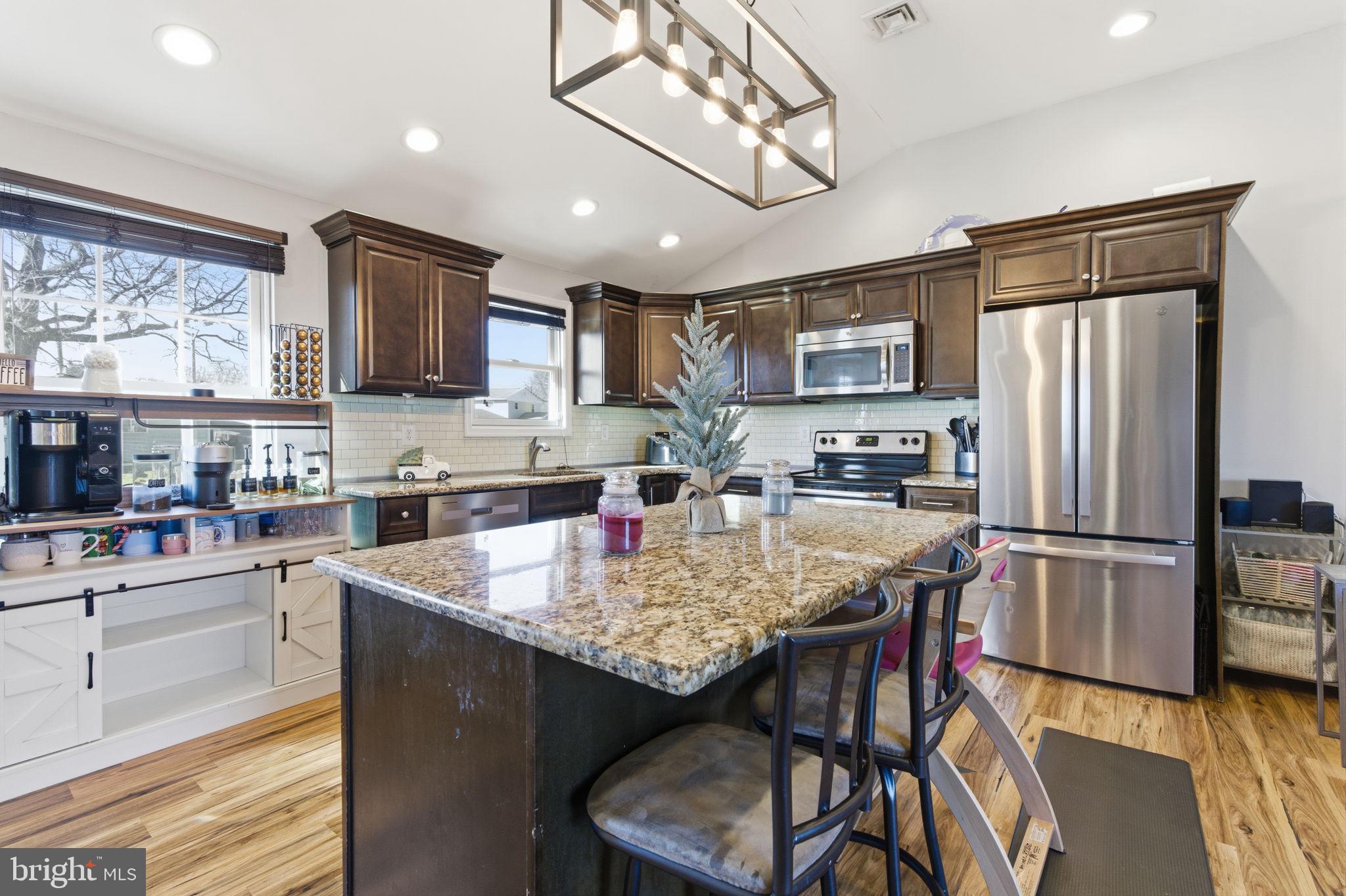 62 Oldbrook Road Levittown, PA 19057 - Photo 1 of 18 a kitchen with stainless steel appliances granite countertop a refrigerator a stove top oven a sink dishwasher a dining table and chairs with wooden floor