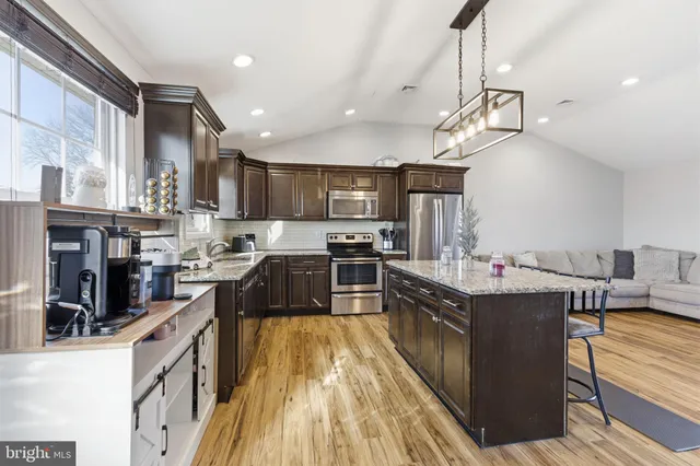 a kitchen with stainless steel appliances granite countertop a sink a stove and a refrigerator