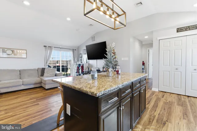 a living room with stainless steel appliances kitchen island granite countertop furniture and a flat screen tv