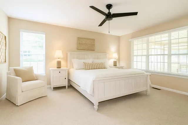 a bedroom with a large bed couch and windows