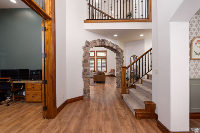 687 South 2080th Street East Springville, UT 84663 - Photo 7 of 149 Spacious entryway featuring wood-finish flooring, a stone archway, and a carpeted staircase with a wood and iron railing