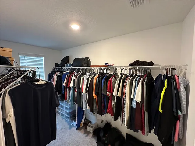 a view of walk in closet with clothes and shoes