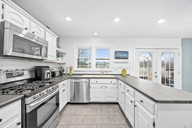 a large kitchen with stainless steel appliances granite countertop a stove and a sink