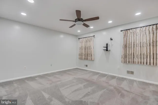 an empty room with windows and fan