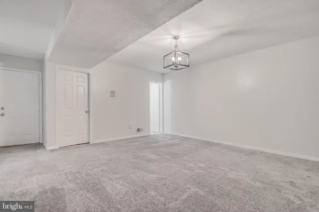 an empty room with a chandelier fan and wooden floor