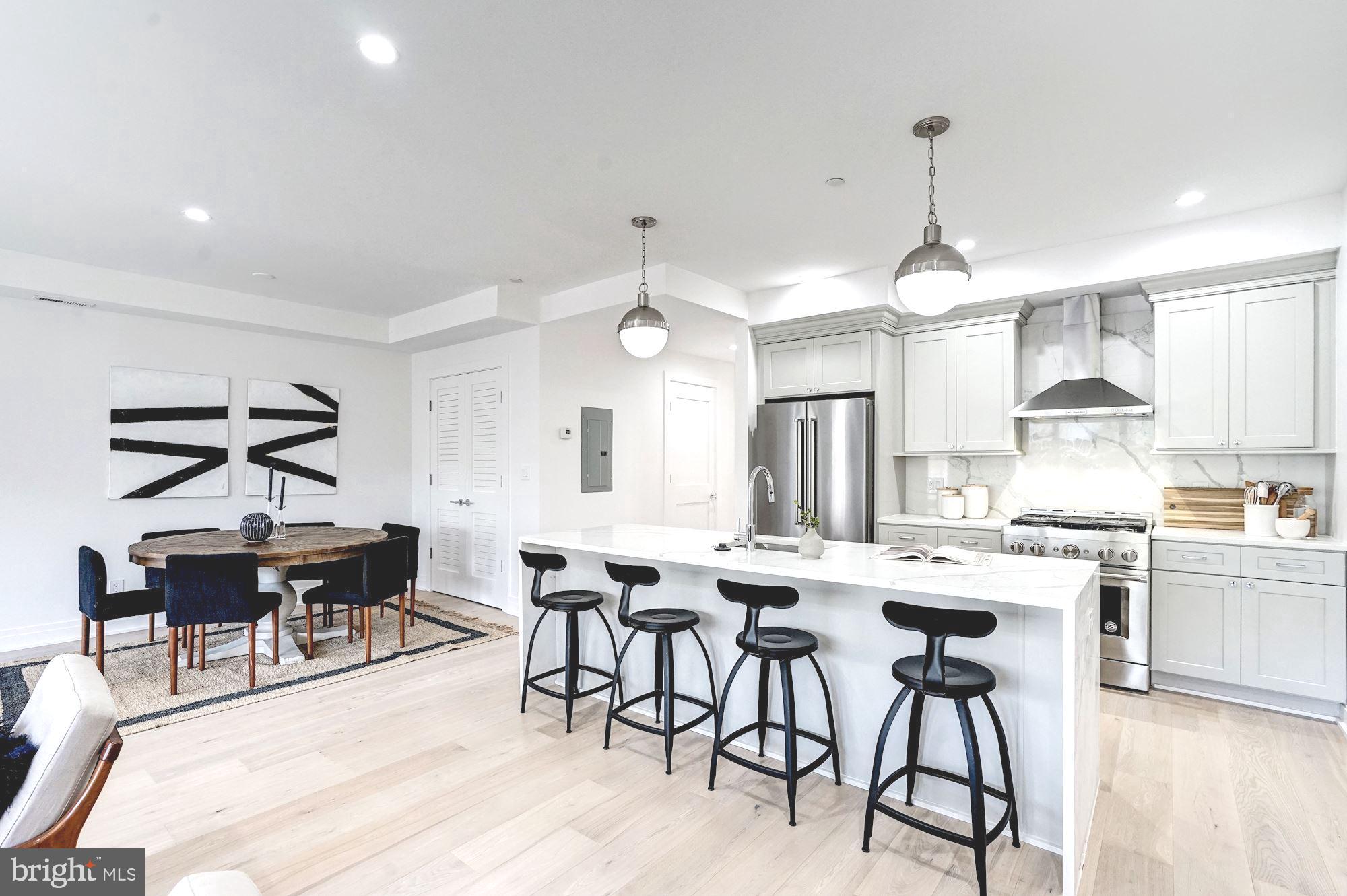 1603 Isherwood Street Northeast, Unit 2 Washington, DC 20002 - Photo 10 of 24 a kitchen with stainless steel appliances kitchen island granite countertop a dining table chairs and white cabinets