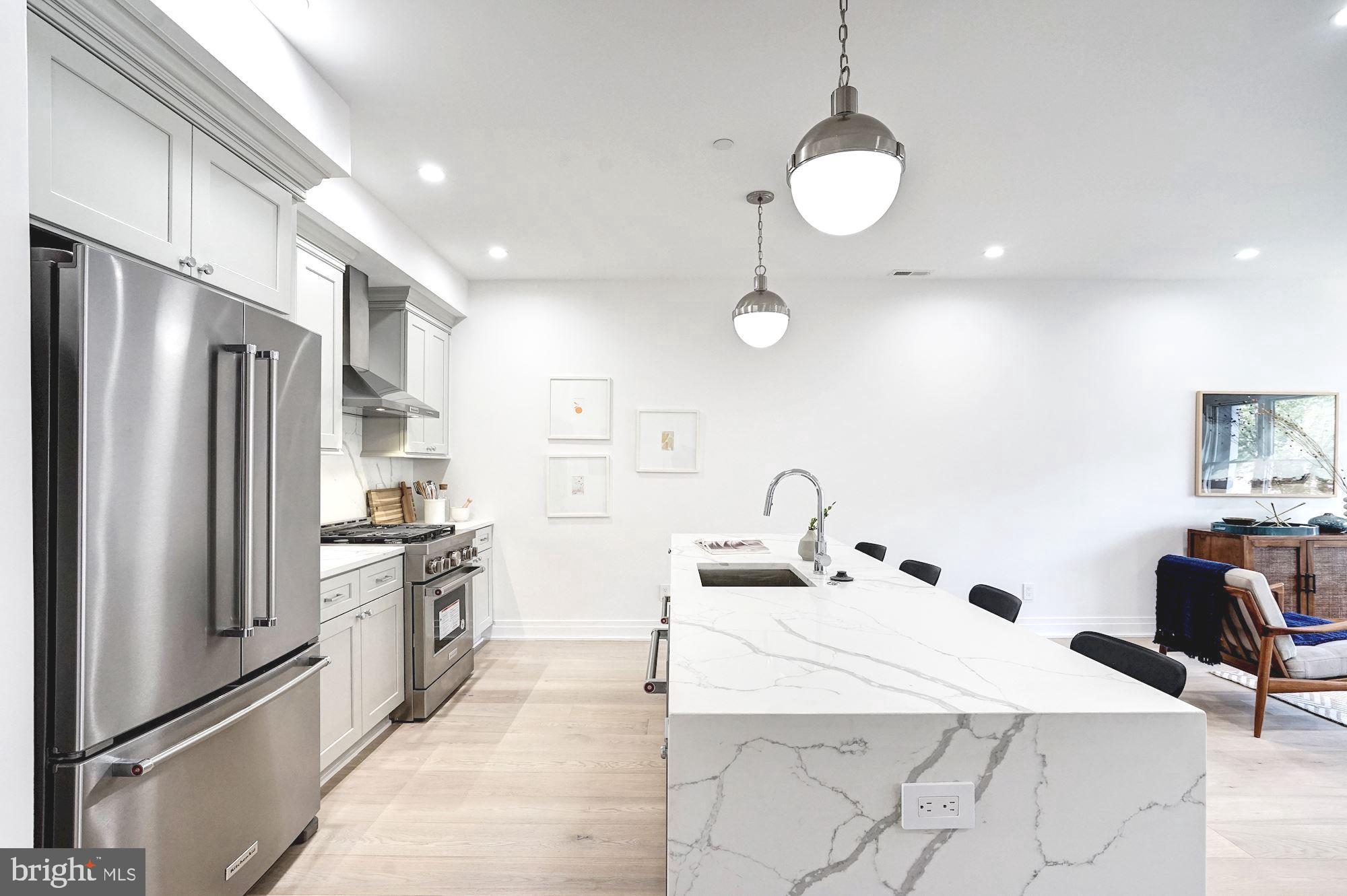1603 Isherwood Street Northeast, Unit 2 Washington, DC 20002 - Photo 12 of 24 a kitchen with stainless steel appliances kitchen island granite countertop a sink refrigerator and cabinets